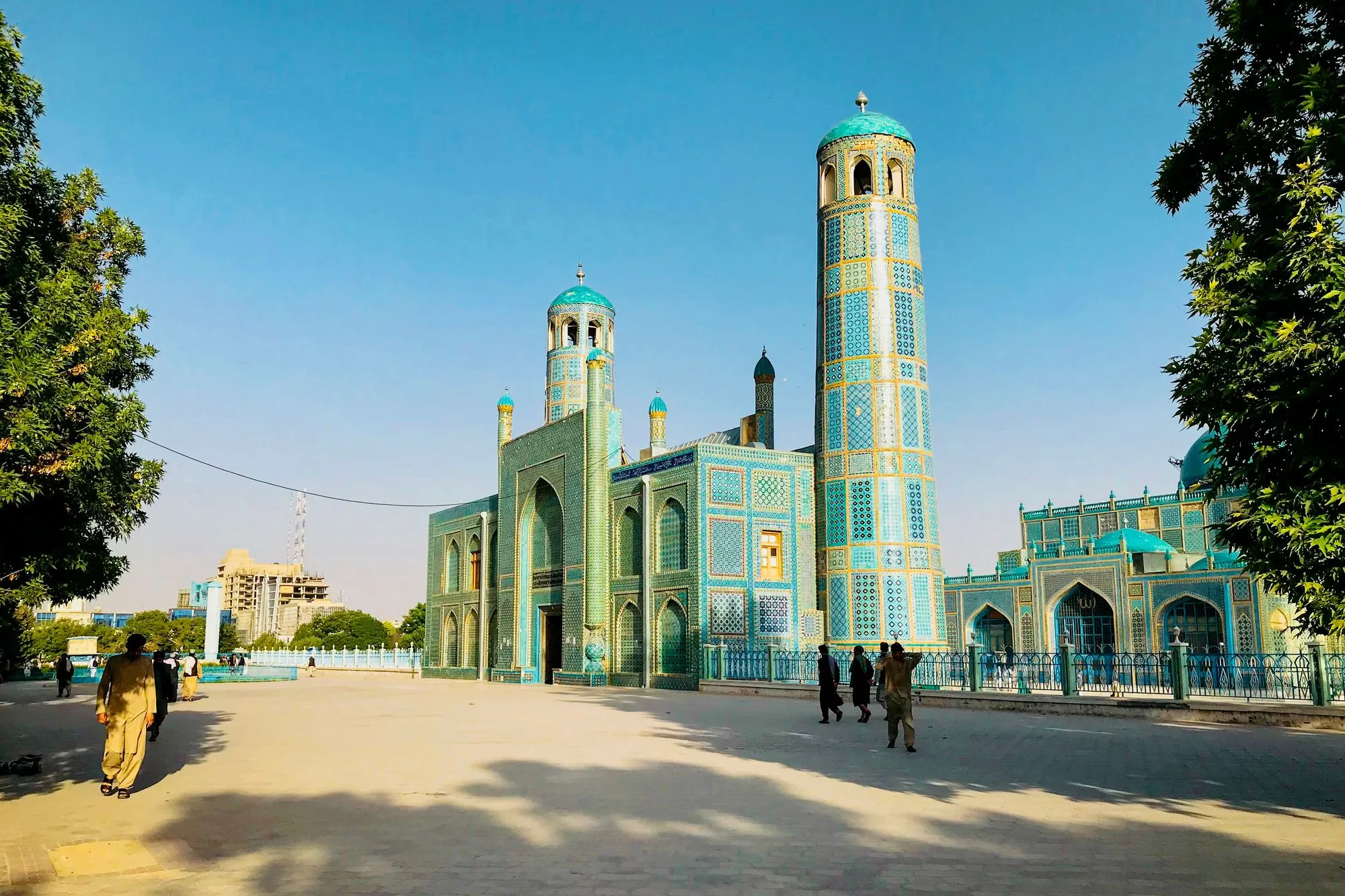 Blaue Moschee in Mazar-i-Sharif mit Minarett und gefliester Fassade, davor Menschen auf dem Vorplatz